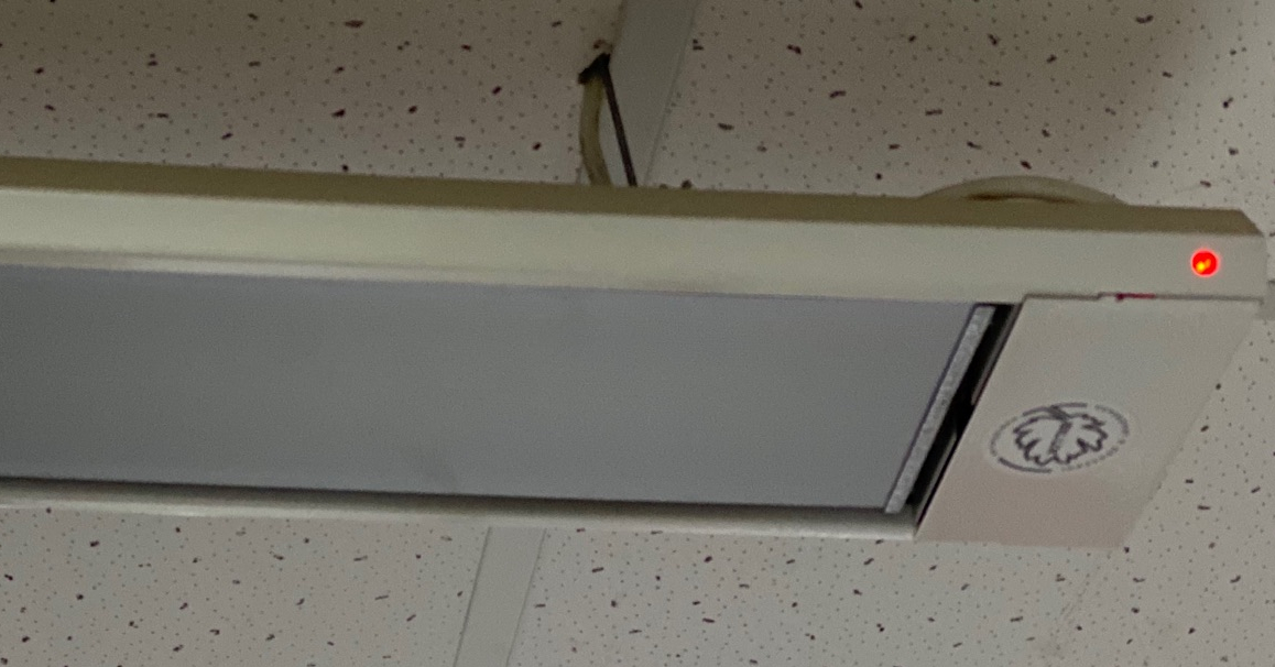 a ceiling mounted long white rectanglar box with a baffled surface facing the floor